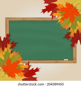 Maple leaves and green chalkboard with chalk in a wooden frame