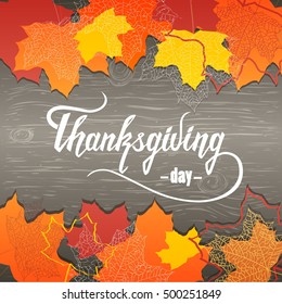 Maple red, yellow and orange leaves with shadows on the gray wooden surfaces. Inscription "Thanksgiving day" in the middle.