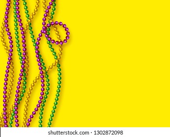 Mardi Gras beads in traditional colors. Decorative glossy realistic elements on yellow background. Copy space, top view. Vector illustration.