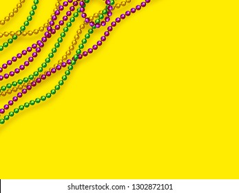 Mardi Gras beads in traditional colors. Decorative glossy realistic elements on yellow background. Copy space, top view. Vector illustration.