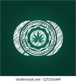 marijuana leaf icon inside chalkboard emblem written on a blackboard