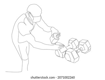 Masked man cleaning dumbbells and equipment in gym to protect from virus. precautions against virus in society