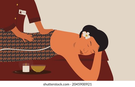 A massager performs a traditional Javanese massage to a jarik-wearing woman using olive oil on a mattress. Jarik is a long cloth with a batik motif.