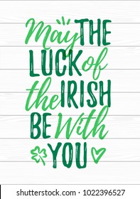 May The Luck Of The Irish Be With You handdrawn dry brush style lettering on white wooden background, 17 March St. Patrick's Day celebration. Suitable for greeting card design, poster, etc., vector