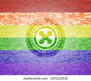 mechanism icon inside emblem on mosaic background with the colors of the LGBT flag