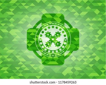 mechanism icon inside green emblem with triangle mosaic background