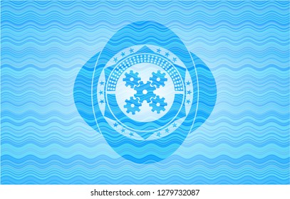 mechanism icon inside light blue water wave style emblem.