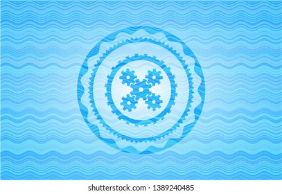 mechanism icon inside light blue water wave style badge.