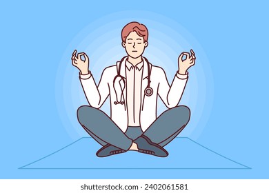 Meditating male doctor sitting in lotus position and taking break to practice stress-relieving yoga. Clinic employee with stethoscope around neck enjoys yoga to increase work productivity.