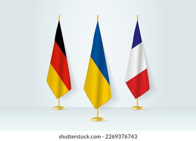 Konzept der Begegnung zwischen der Ukraine, Deutschland und Frankreich. Flaggen auf einem Flaggenstand.