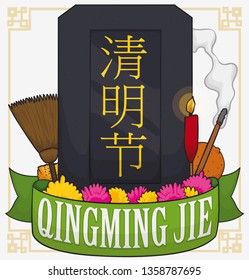 Memorial dark tombstone with commemorative ribbon and elements to celebrate Qingming Jie (written in Chinese calligraphy) Festival: orange, incense, flowers, lighted candle, cleaning sponge and broom.
