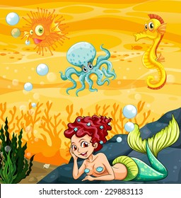 A mermaid under the sea with the other sea creatures