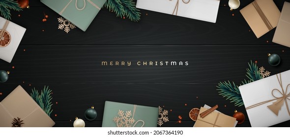 Merry Christmas banner. Flat lay composition with fir tree branch, cinnamon, orange slice, berries, gift craft box, envelope and pine cone on black wooden floor. Scandinavian style. 