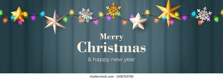 Merry Christmas banner with garland on blue wooden ground. Lettering can be used for invitations, post cards, announcements