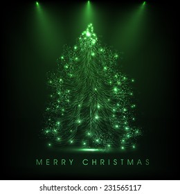 Merry Christmas celebration concept with shiny X-mas tree in spot light on green background.