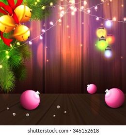 Merry Christmas celebration with glossy Xmas Balls, golden Jingle Bells, Fir Tree branch and illuminated lights on elegant wooden background.