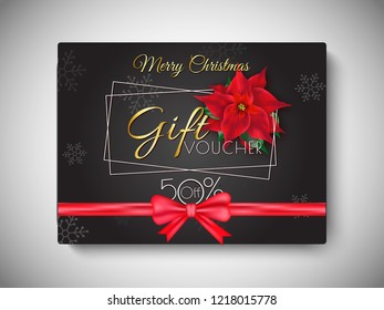 Merry Christmas gift voucher with 50% discount offer, flowers and shiny red ribbon decorated on black background for Festival celebration.