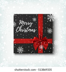 Merry Christmas greeting card template. Realistic black gift icon, top view on winter background with snow and snowflakes. Vector illustration.