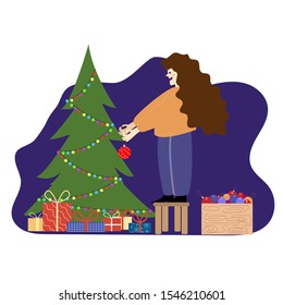 Merry Christmas and Happy Holidays. Woman holding a festive ball Stand on Chair Decorate Christmas Tree Indoors Put ball on Xmas. Nearby are gifts and a box with Christmas toys.