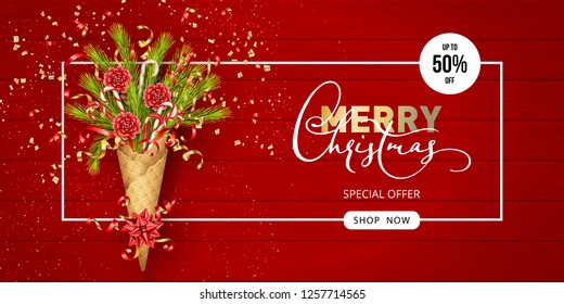 Merry Christmas and Happy New Year composition in a waffle cone of coniferous branches. Festive Christmas tree decorations on wooden red background. Christmas sale banner