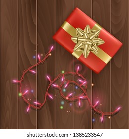 Merry christmas or happy new year day greeting card with a red gift box with gold bow on wooden background, Holiday decoration element. Vector Eps 10 illustration.