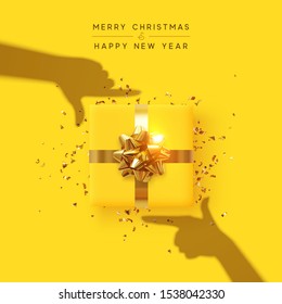 Merry Christmas and Happy New Year. Yellow background with realistic festive gifts box. Effect of the shadow of hands is holding a gift in focus. Photo Frame Hands Made by Young Girls. Xmas present
