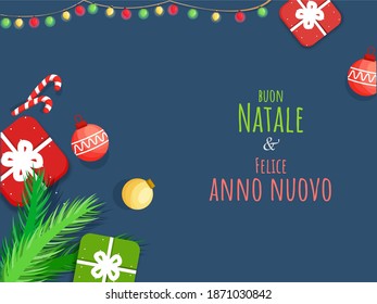 Merry Christmas And Happy New Year Text Written Italian Language With Top View Of Gift Boxes, Baubles, Candy Cane, Fir Leaves Decorated On Blue Background.