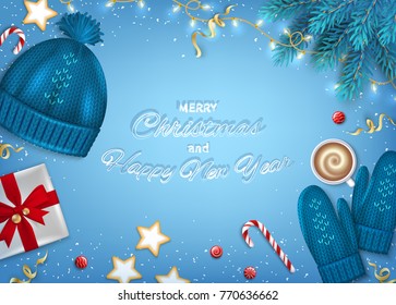Merry Christmas and Happy New Year Greeting card. Winter Elements fir branches, knitted blue hat, mittens, cocoa cup, paper gift box, sweets, garlands, ribbons on blue background. Top View Vector