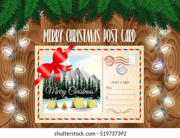 Merry Christmas post card design on the wood table with Christmas tree branches and garland lights. Camping in mountains landscape.