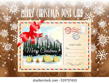 Merry Christmas post card design. Merry Christmas post card on the wood table and snowflakes. Camping in mountains landscape.