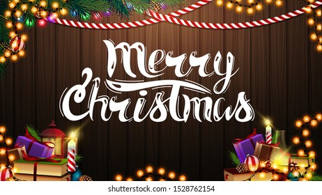 Merry christmas postcard with garland, Christmas tree branch, books and candle in the wooden background