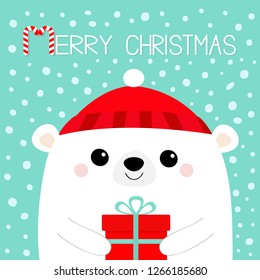 Merry Christmas. White polar bear head face holding gift box. Red hat. Happy New Year. Cute cartoon kawaii baby character. Funny animal. Flat design. Hello winter. Blue snow background. Vector