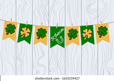 Merry garland of green and yellow little flags, clover leaves and Tag "St Patrick's". Decorations for St. Patrick's Day. Vector Stock Illustration with flags on clothespinson a light green wood.