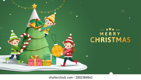 Merry Xmas Banner In 3d Paper Art. Cute Christmas Elves Are Decorating Christmas Tree In Snow.