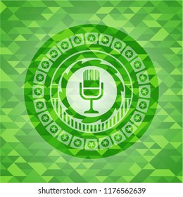 microphone icon inside realistic green emblem. Mosaic background