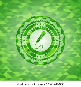 microphone icon inside realistic green emblem. Mosaic background