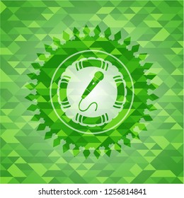 microphone icon inside realistic green emblem. Mosaic background