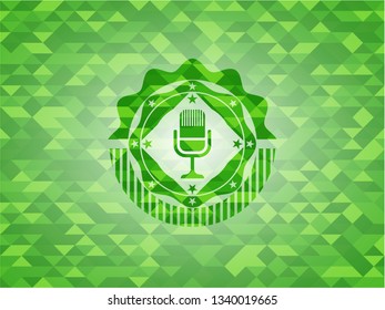 microphone icon inside realistic green emblem. Mosaic background