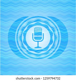 microphone icon inside sky blue water style emblem.