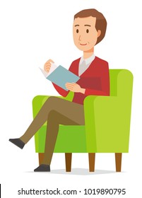 A middle-aged man wearing a sweater is reading on a sofa