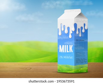 Milk package on wooden table on background of blurred landscape. Cow milk gable top carton with meadow and sky