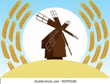 Mill on the background of the wheat fields and wheat ears, sun and blue sky