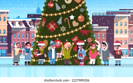 mix race children group near decorated fir tree city building houses winter street cityscape merry Christmas happy new year concept flat horizontal vector illustration