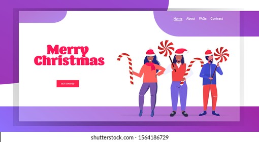 mix race people in santa claus hats holding sweetmeats candy cane and lollipop merry christmas happy new year winter holidays celebration concept horizontal copy space greeting card full length vector