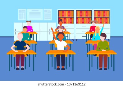 mix race pupils sitting desks raising hands during lesson education concept modern elementary school classroom interior full length flat horizontal