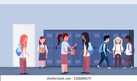 mix race schoolchildren group standing in school lobby corridor interior with row of blue lockers communication education concept horizontal full length flat