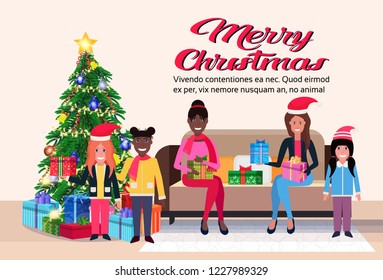mix race women with children sitting on couch modern living room merry christmas happy new year decorated gift boxes pine tree flat horizontal copy space vector illustration