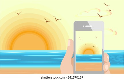 Mobile phone capturing the sunrise beach