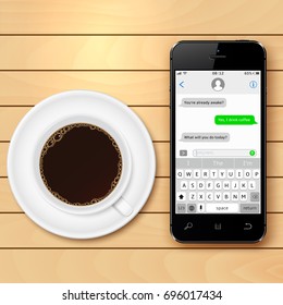 Mobile phone with sms chat on screen and coffee cup on wooden table