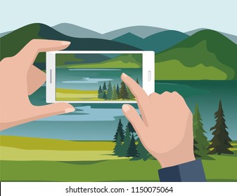 Mobile photography concept. Man taking photos of nature landscape with fir trees and river to phone.	
